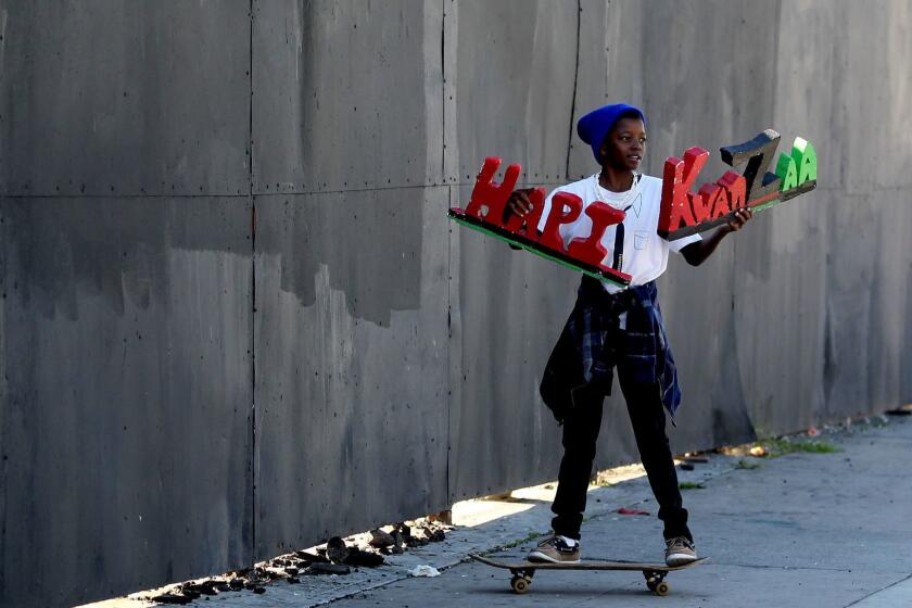 LOS ANGELES, CALIF. - DEC. 26, 2014. Qattro Davis, 11, participates in the 38th KwanZaa Gwaride Parade along Crenshaw Boulevard on Friday, Dec. 26, 2014. Participants included maskers, bicyclists and car enthusiasts, as well as community members carrying signs that focused on issues like police brutality, residential foreclosures, judicial corruption, transparency in government, political prisoners and racism. The march was organized by Kwanzaa People of Color, and ended with a "Black Lives Matter'' rally at Leimert Park (Luis Sinco/Los Angeles Times)