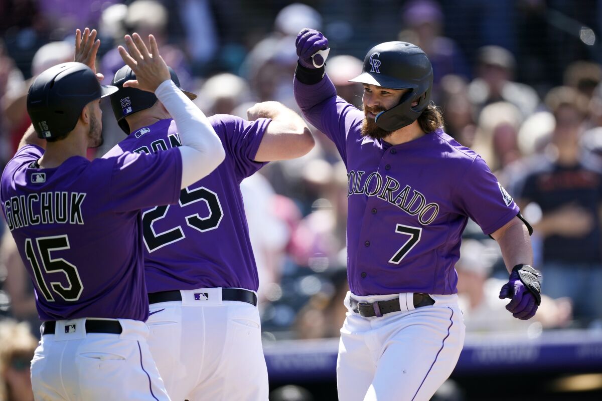 Colorado Rockies' Brendan Rodgers, right, celebrates with C.J. Cron, center, and Randal Grichuk after after hitting a three-run home run in the fifth inning of a baseball game against the Washington Nationals, Thursday, May 5, 2022, in Denver. (AP Photo/David Zalubowski)