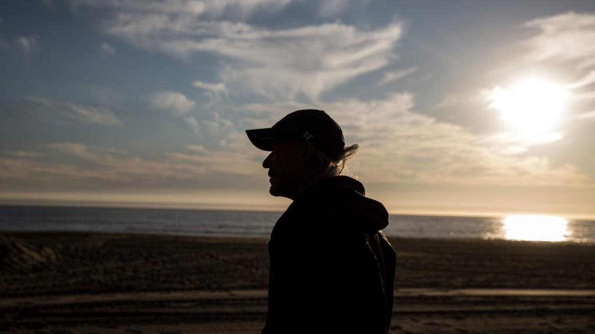 Maurice Smith, who lives at a concession stand near Zuma Beach, is silhouetted by the setting sun.