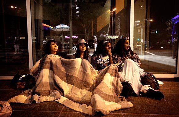 From left, Hannah Chavez, 16, Orpha Chavez, 18, Tikeira Tillis, 13, and her mom, Celesia Allison, wake up in the early morning hours on Olympic Boulevard after arriving the night before for the public memorial service.