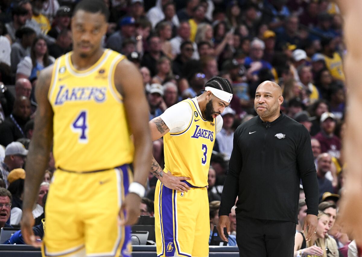Lakers forward Anthony Davis, center, talks with head coach Darvin Ham, right, along the sideline during a break in play.