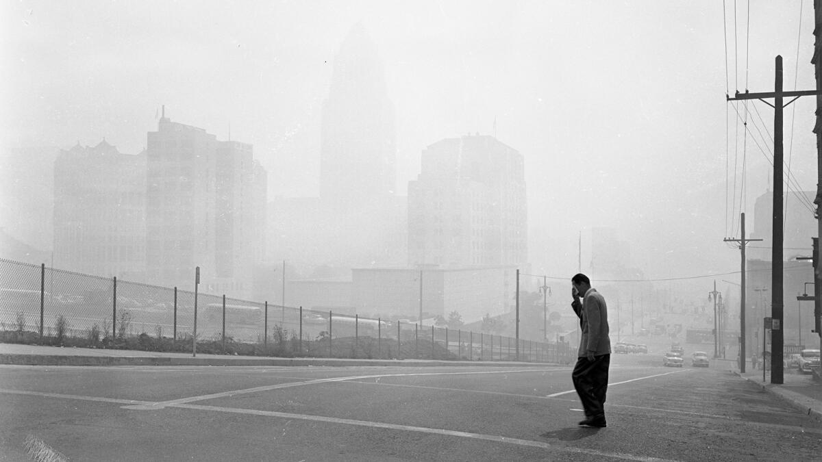 In 1955, downtown L.A. buildings are barely visible from 1st and Olive streets at the peak of heavy smog. Faintly visible from left are the Hall of Records, law building, new county law library and state building, with City Hall in background.
