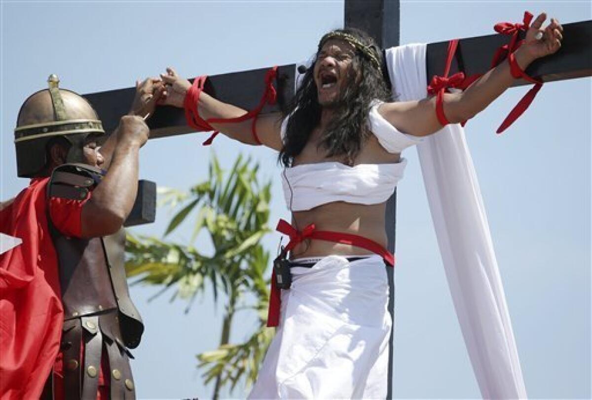Filipino penitent Ruben Enaje, who has portrayed as Jesus Christ for 27 times, reacts as a nail is removed from his hand after being crucified during Good Friday rituals on March 29, 2013 at Cutud, Pampanga province, northern Philippines. Several Filipino devotees had themselves nailed to crosses Friday to remember Jesus Christ's suffering and death, an annual rite rejected by church leaders in this predominantly Roman Catholic country. (AP Photo/Aaron Favila)