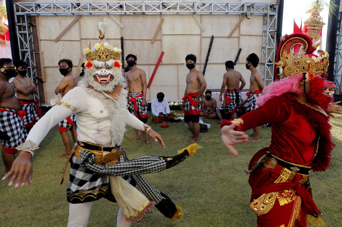 Bailarines disfrazados se preparan para ejecutar una danza tradicional durante un desfile en Bali, 