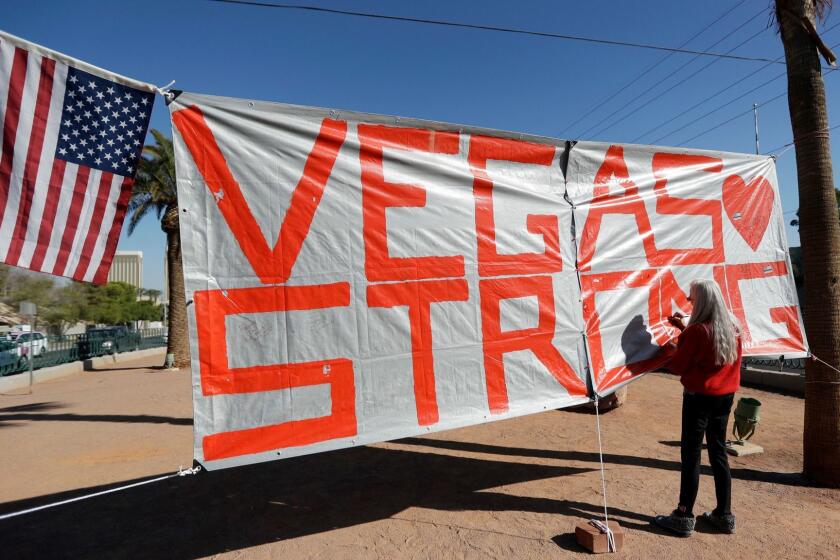 FILE - In this Oct. 5, 2017, file photo, Las Vegas resident Nancy Cooley signs a Vegas Strong banner honoring the victims of a mass shooting in Las Vegas. The official slogan of Las Vegas, "What happens here, stays here," is back by popular demand. The destination's tourism agency revived the 15-year-old slogan this week, three months after it was put on hold following the October mass shooting. Stephen Paddock opened fire from the hotel on an outdoor country music concert, killing 58 and injuring hundreds. (AP Photo/Gregory Bull, File)