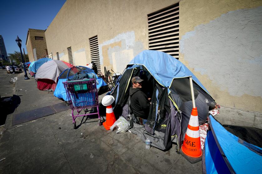 San Diego, CA - August 04: On Friday, Aug. 4, 2023, at an encampment in the East Village on 16th Street, Juliana Egipto and Robert Padilla prepare to settle in before it gets dark. The two have been living on the streets for the past eight years. (Nelvin C. Cepeda / The San Diego Union-Tribune)
