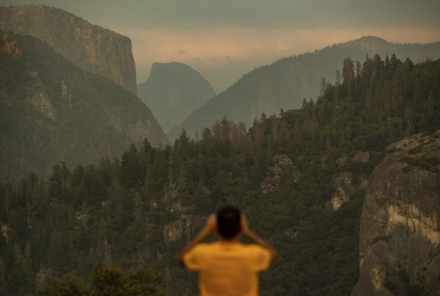 Francisco Avendano, visiting from Madrid, photographs Half Dome as smoke from the Ferguson fire hangs over Yosemite National Park. Parts of the park, including Yosemite Valley, will close Wednesday as firefighters work to contain the blaze.