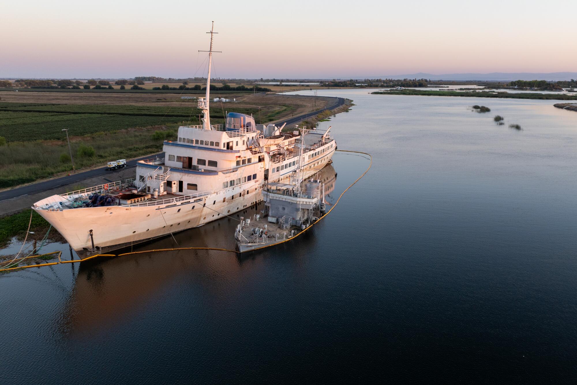 The MS Aurora, surrounded by a protective oil boom, is moored in a remote slough