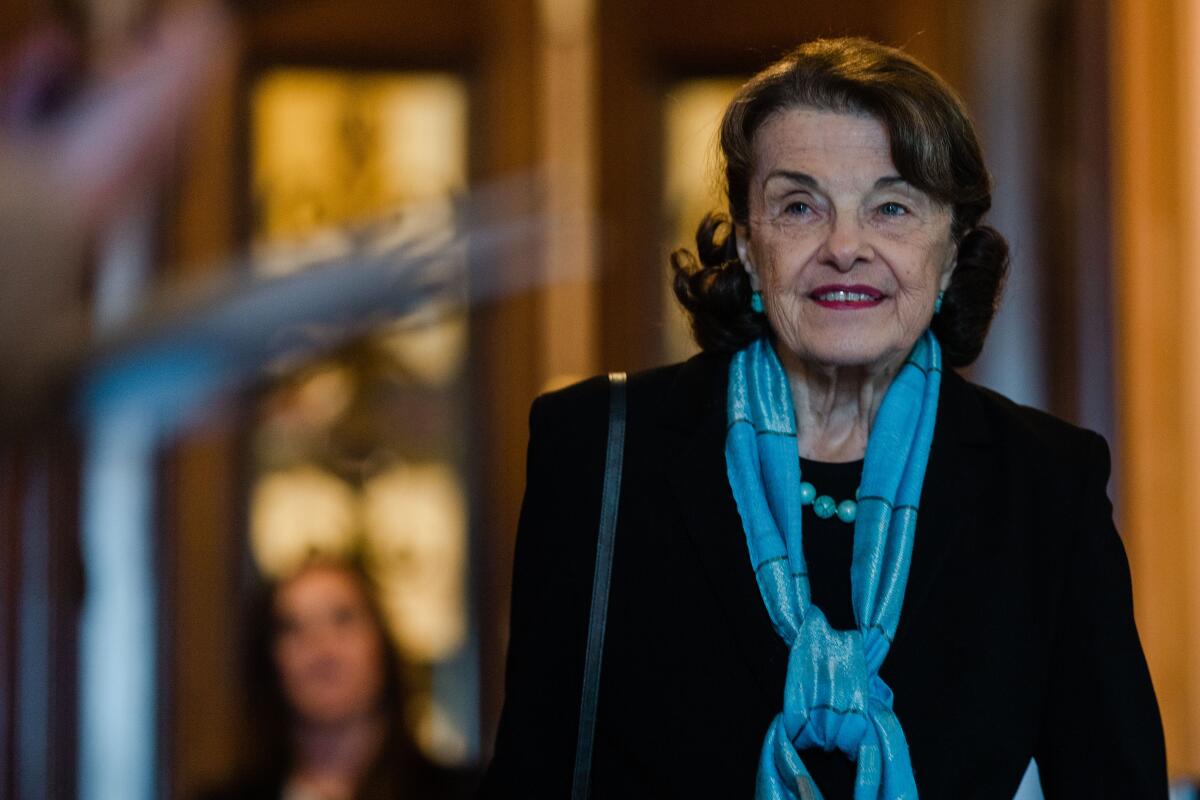 Sen. Dianne Feinstein walks down a hall in a blue scarf.