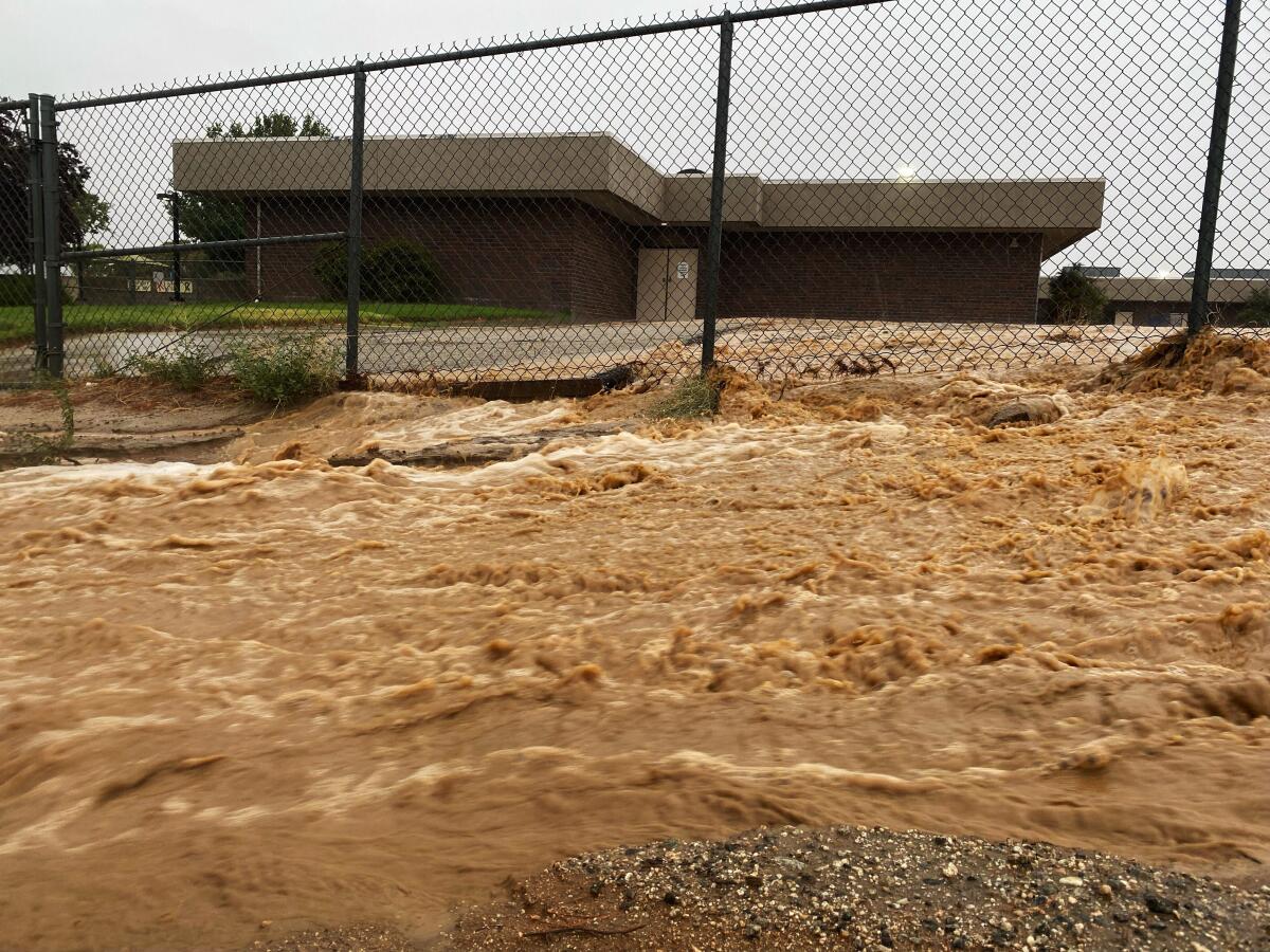 Flood water rush past an elementary school campus. 