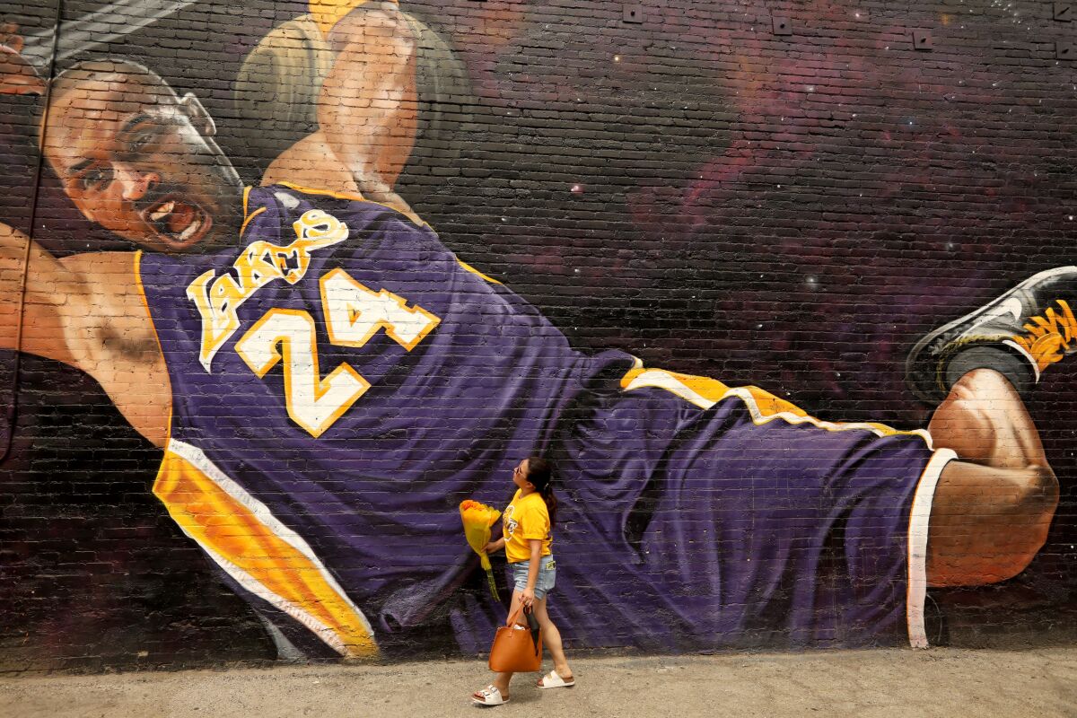 A large mural of Kobe Bryant in a purple Number 24 Lakers jersey on a brick wall
