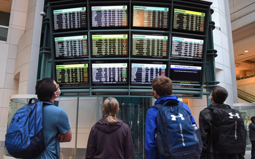 Travelers look at a display board showing canceled and delayed flights at Orlando International Airport