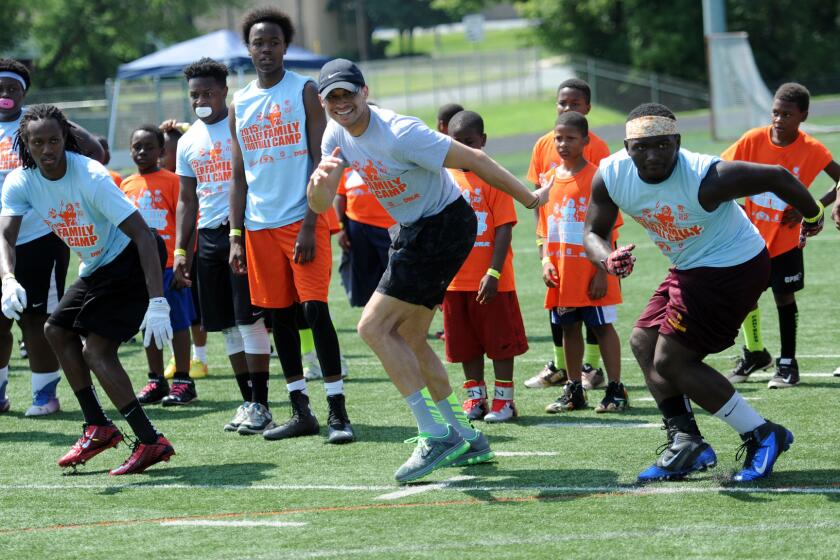 Vincent Fuller Jr. (center, wearing black baseball cap) shows his form as he joins in on a drill. Fuller, a former NFL player, his parents and brothers, hosted the Fuller Family Football Camp at Woodlawn High School for players ages 8-18 on Saturday, July 11, 2015.