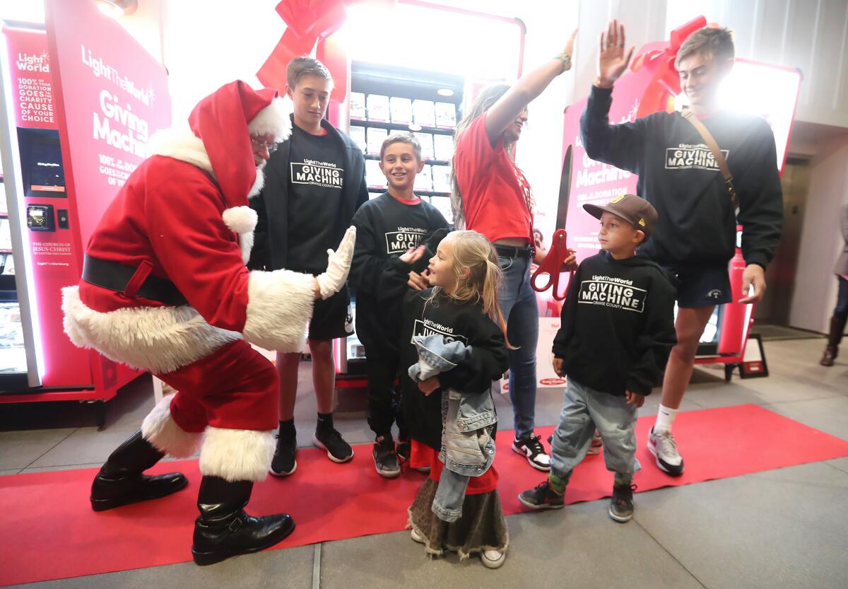 Santa high-fives Rose Stokes with the rest of the family after they brought Giving Machines to SoCal.