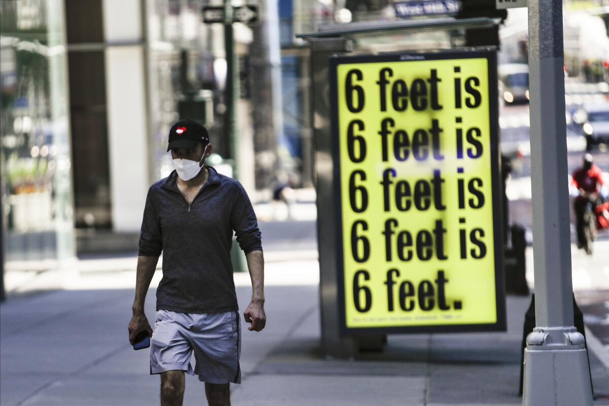 A pedestrian walks past a social-distancing reminder in New York.