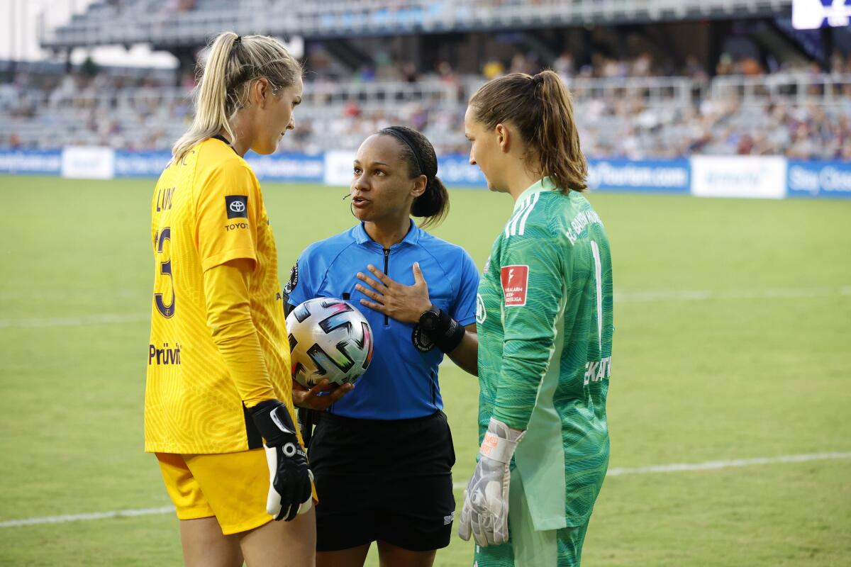 Referee Natalie Simon speaks with Katie Lund of Racing Louisville FC and Laura Benkarth of FC Bayern Munich. 