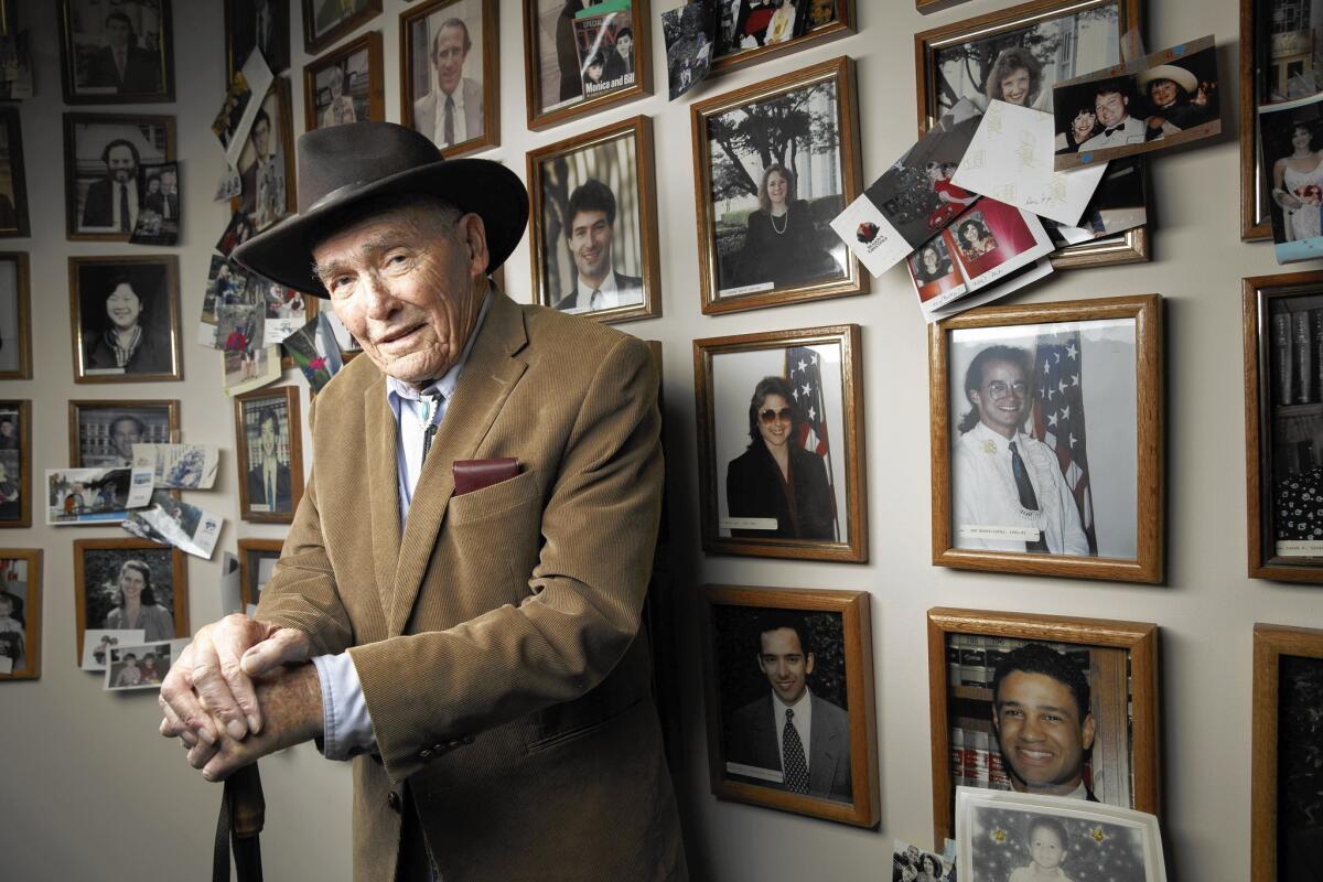 Harry Pregerson, a judge on the U.S. 9th Circuit Court of Appeals, poses in front of photos of the 136 law clerks who worked for him during his 50-year career. Now 92, he is stepping down from the bench, a decision he said he made with “very mixed feelings.”