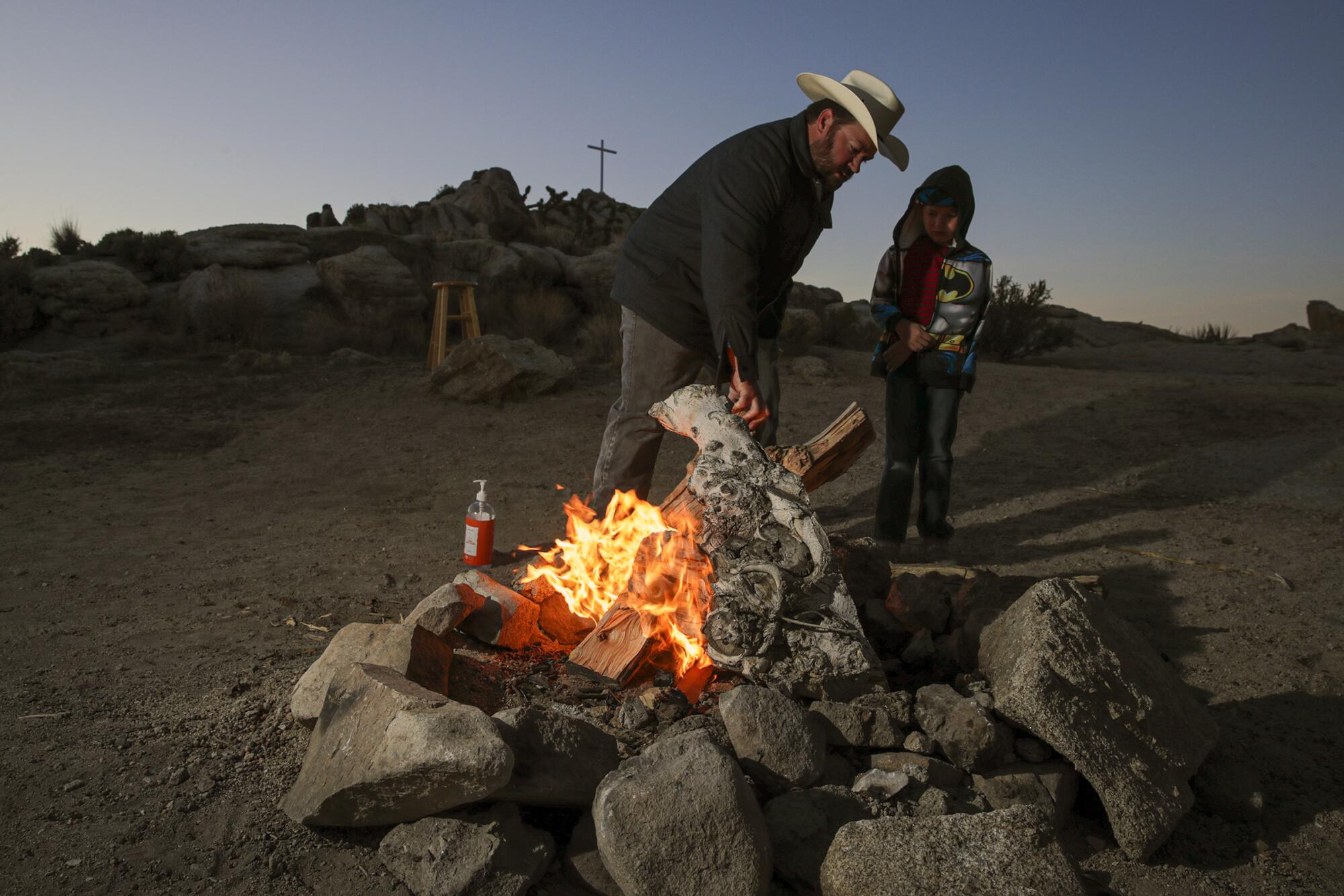 A man and his son around a campfire in a rock pit in the desert