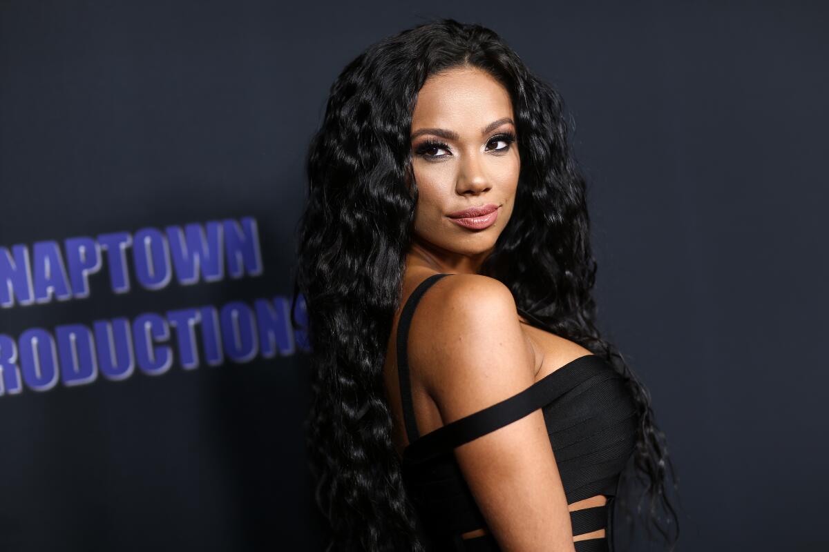 Erica Mena looks over her shoulder while posing in a black dress.
