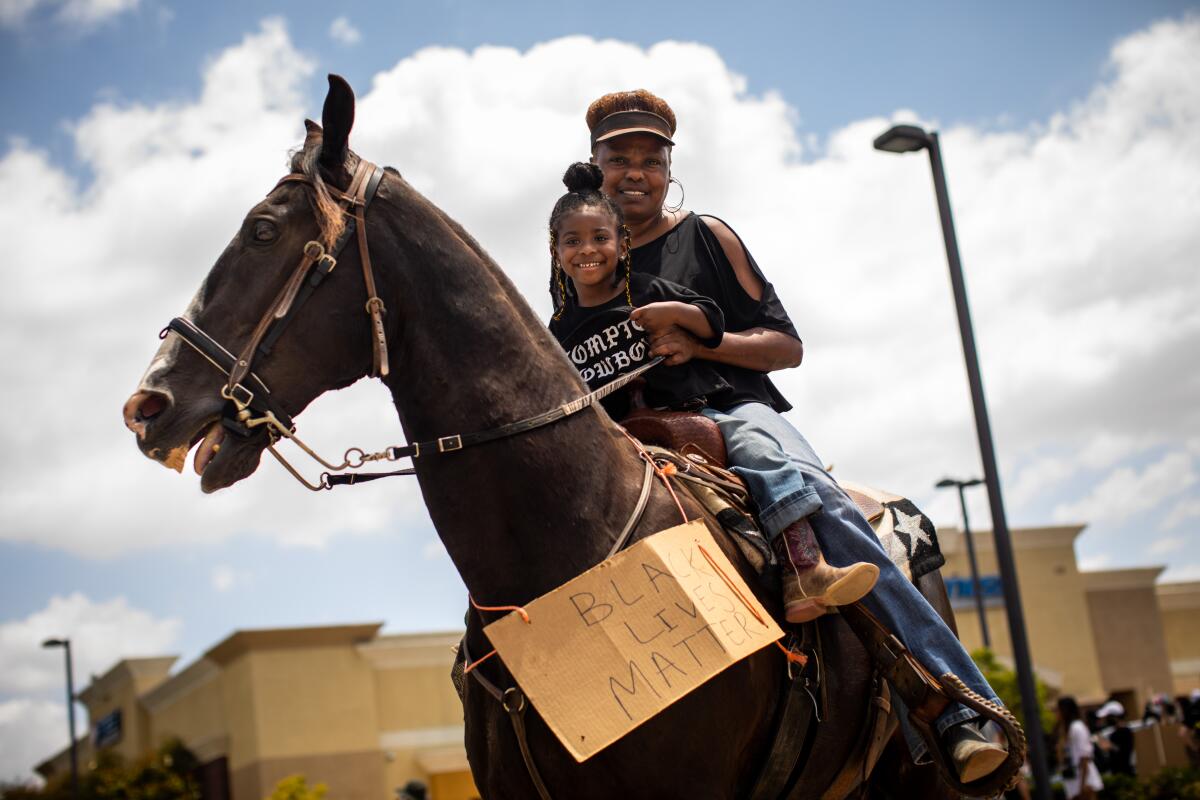 Taylor Rahye Wade, 3, daughter of Keiara Wade, an official Compton Cowboy, rides with her grandmother, Jennifer McClendon.