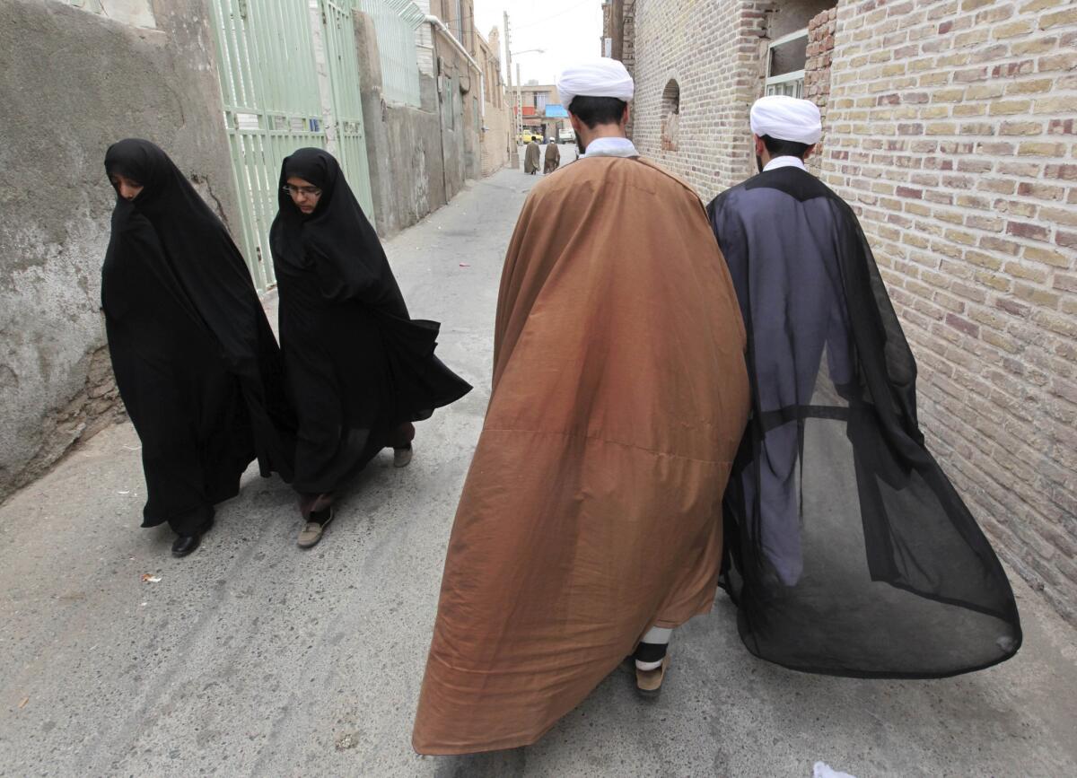 Two clerics pass two women in an alley in the eastern Iranian city of Birjand last week.