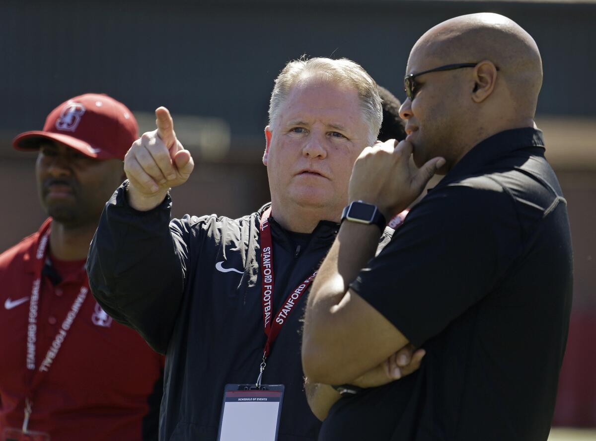 San Francisco Coach Chip Kelly gestures while talking with Stanford Coach David Shaw, right, during Stanford's NFL Pro Day on March 17.