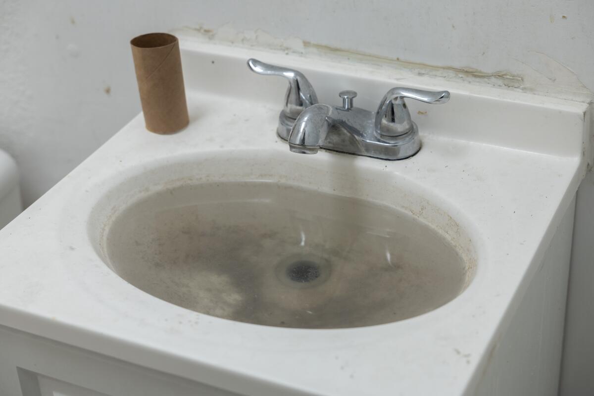 A clogged sink in a community bathroom.