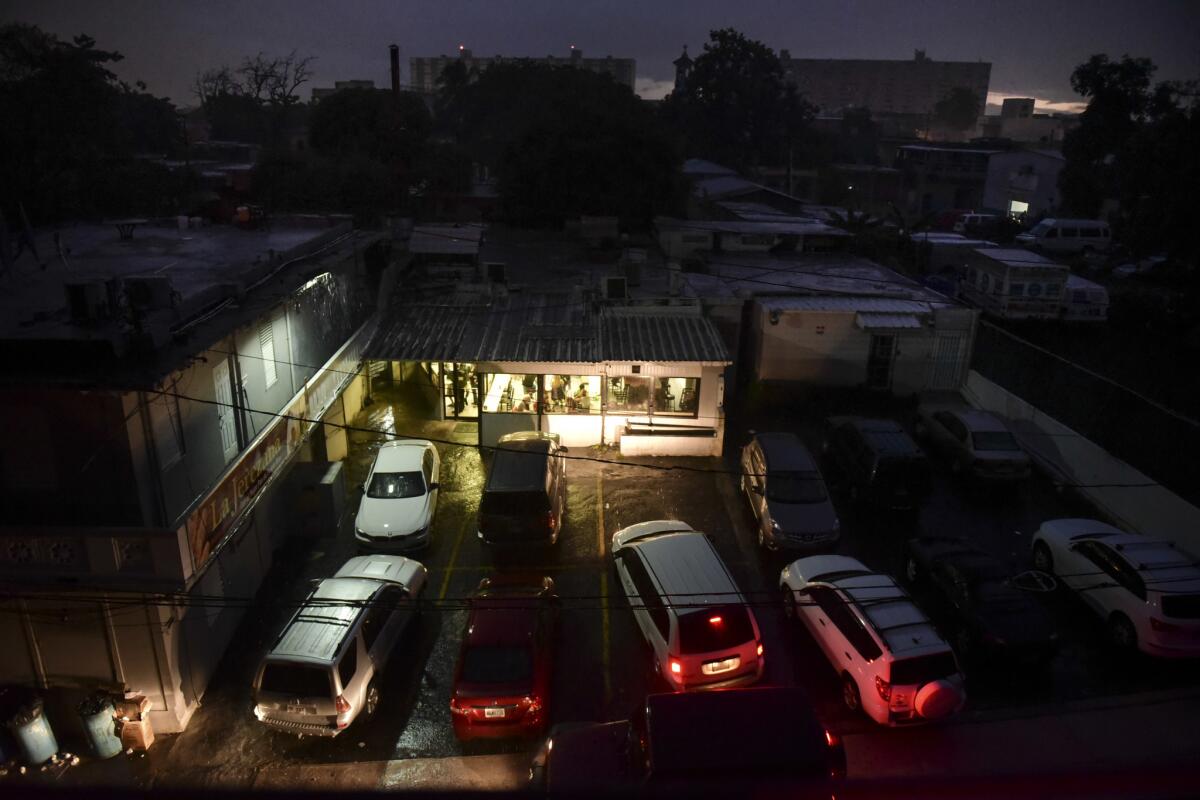 Motorists illuminate a storefront with their headlights as they drive in to buy bread after a massive blackout in San Juan, Puerto Rico, on Thursday.