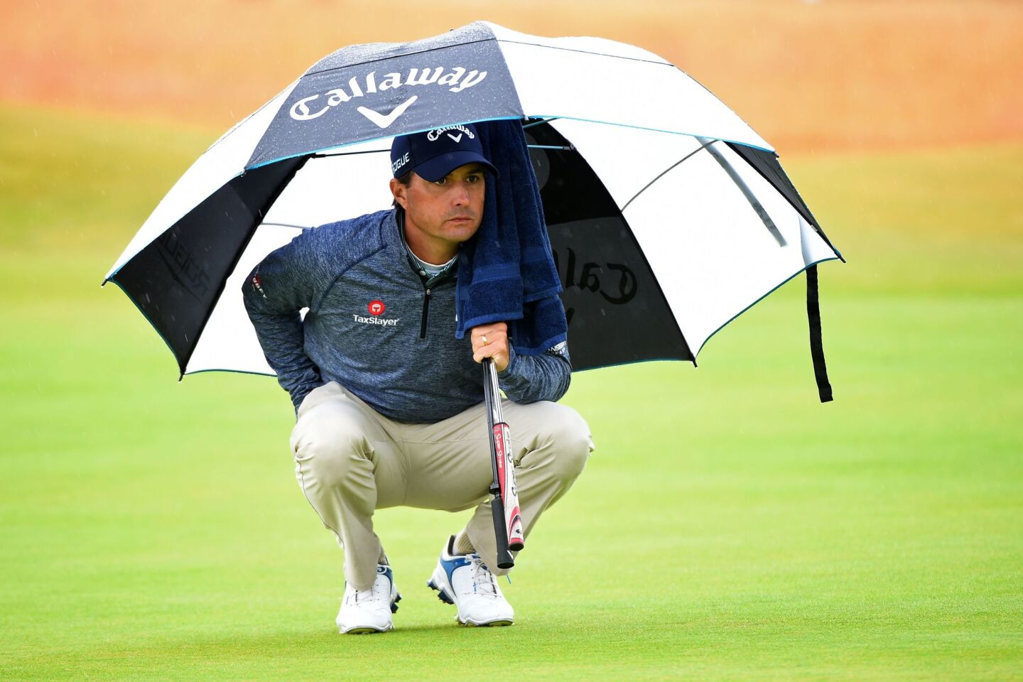 Kevin Kisner shelters from the rain on the fifth green Friday during the second round of the British Open in Carnoustie, Scotland.