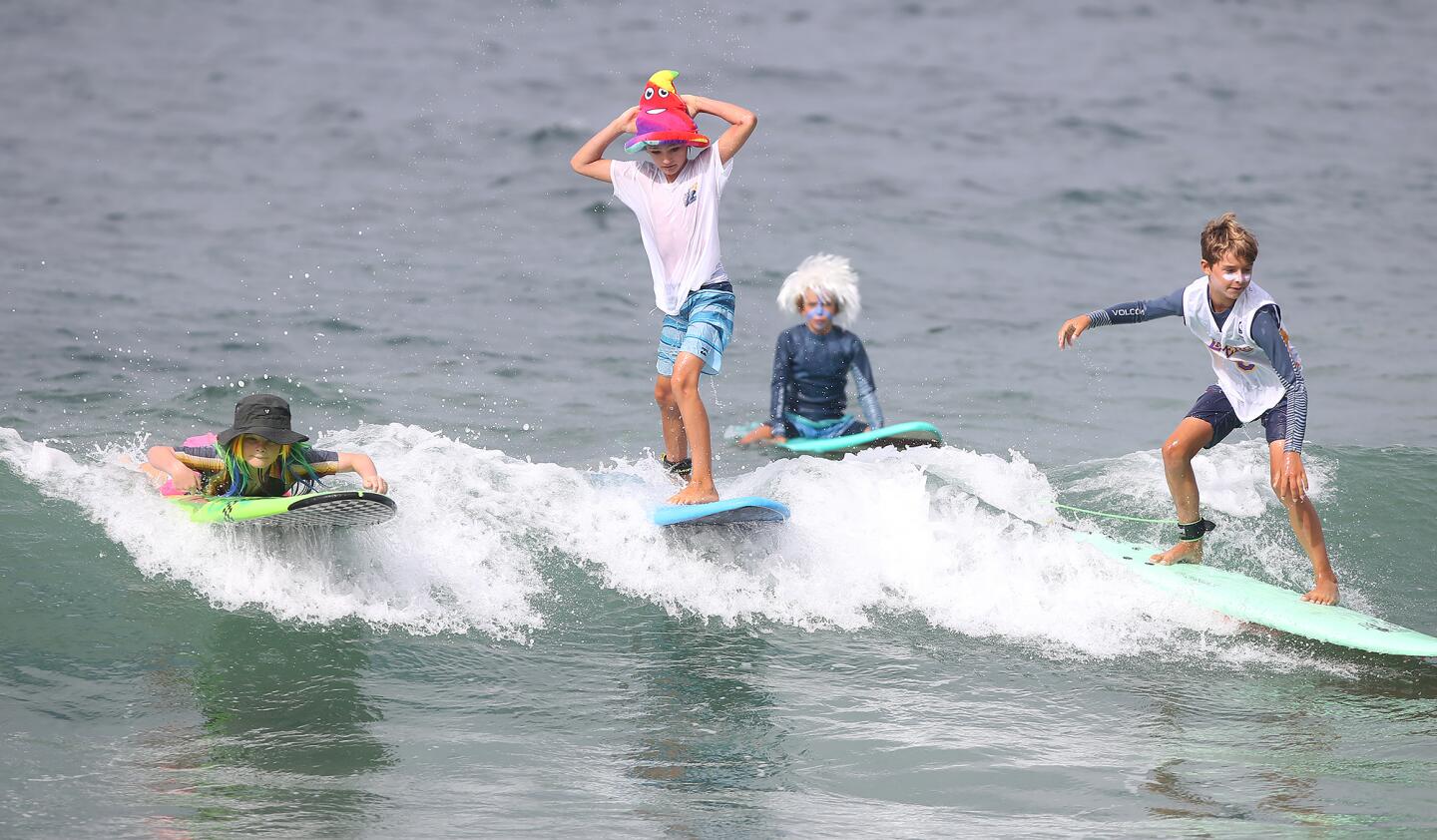 Kids ride the foam dressed as emojis during the Laguna Beach Surf School summer camp Friday in Laguna Beach.