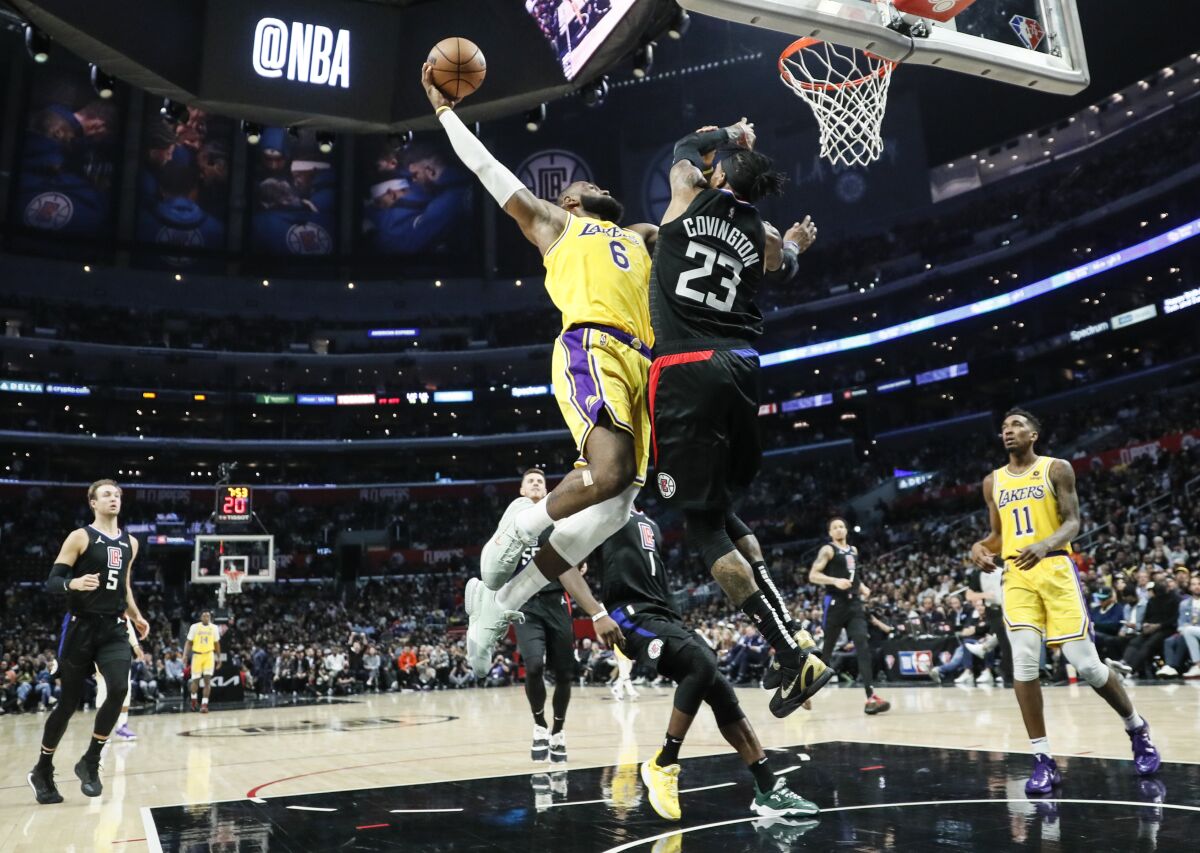Lakers forward LeBron James elevates for a dunk attempt while defended by Clippers forward Robert Covington.