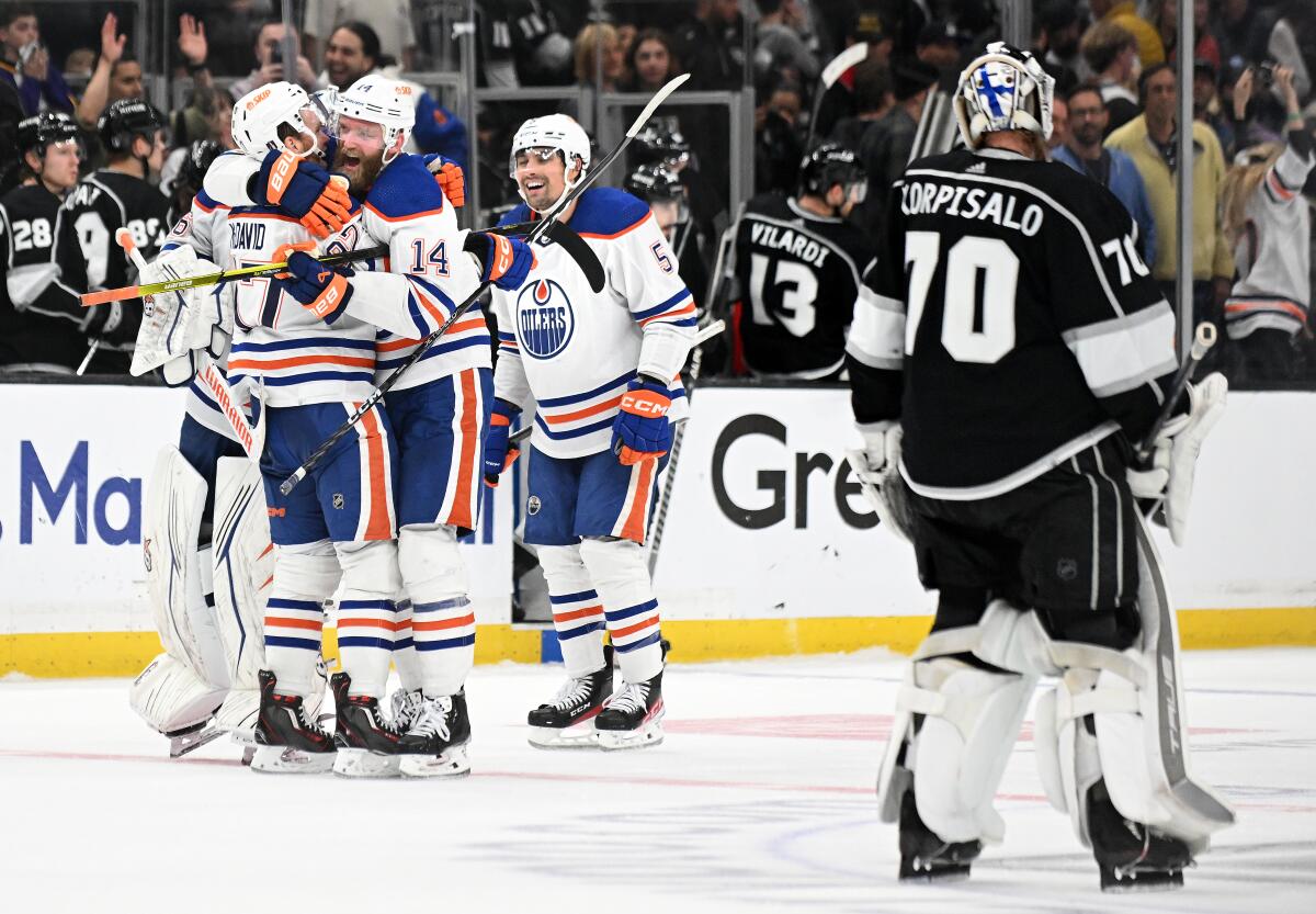 Kings goalie Joonas Korpisalo skates off the ice as the Oilers celebrate Zach Hyman's overtime goal.