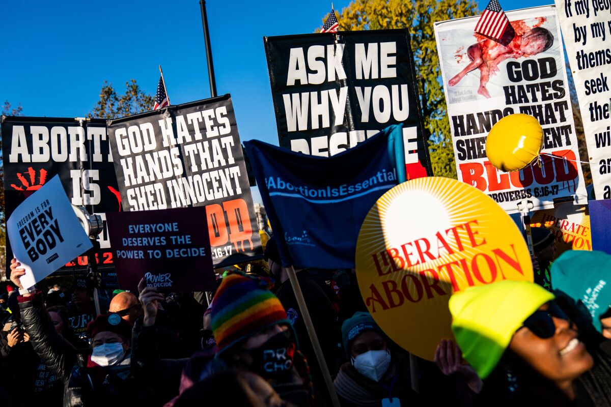 Protestors carry signs advocating and protesting against abortion.