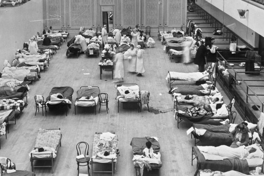 In this 1918 photo made available by the Library of Congress, volunteer nurses from the American Red Cross tend to influenza patients in the Oakland Municipal Auditorium, used as a temporary hospital. As scientists mark the 100th anniversary of the Spanish influenza pandemic, labs around the country are hunting better vaccines to boost protection against ordinary winter flu and guard against future pandemics, too. (Edward A. "Doc" Rogers/Library of Congress via AP)