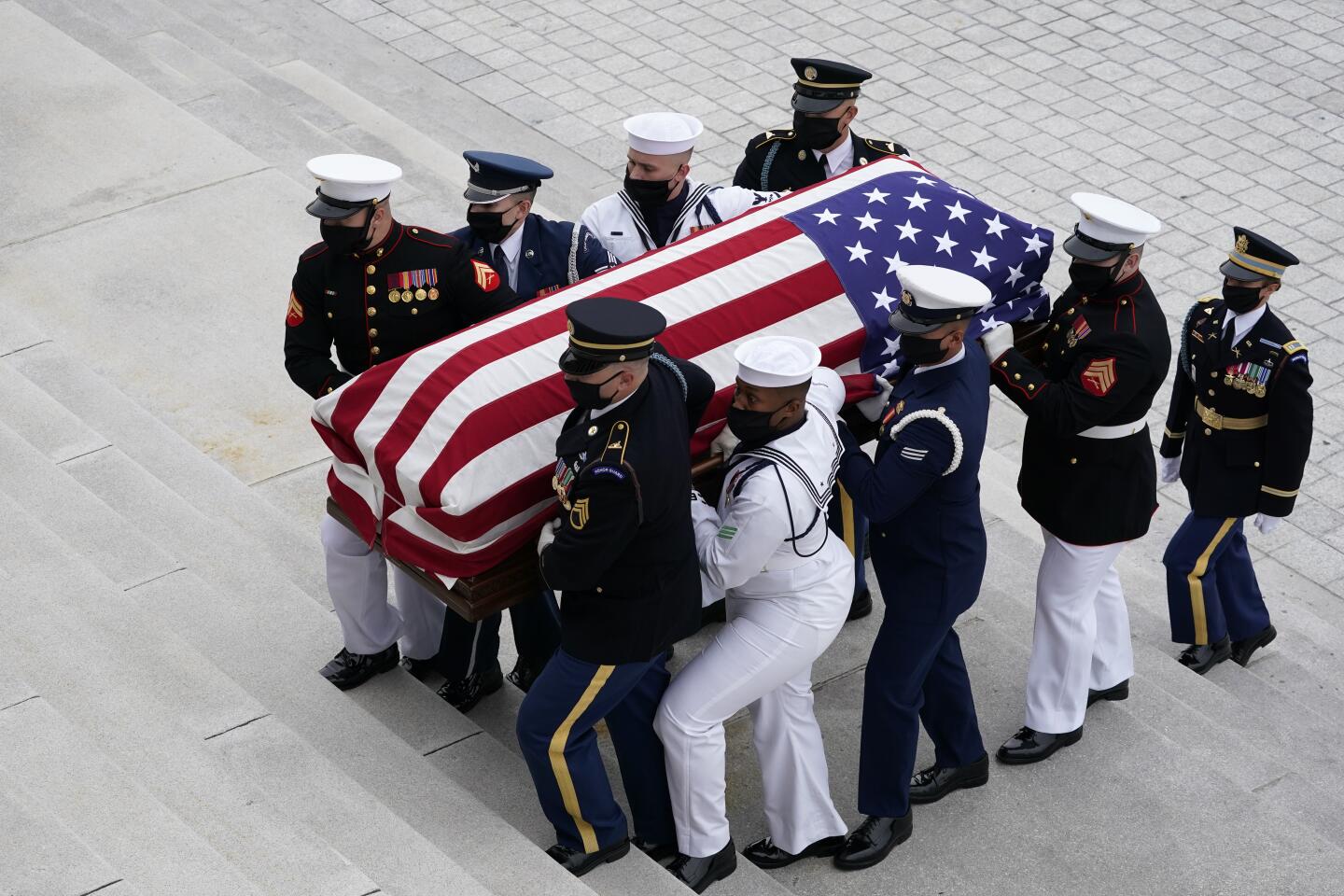 A military honor guard carries the flag-draped casket of Justice Ruth Bader Ginsburg to lie in state at the U.S. Capitol.