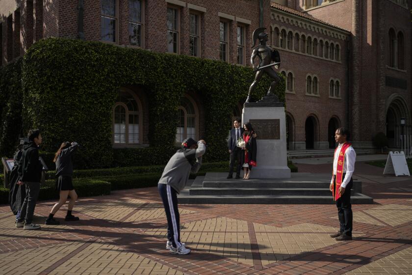 Graduating seniors take photos around the Tommy Trojan statue on the University of Southern California campus in Los Angeles, Thursday, April 25, 2024. The university canceled its main graduation ceremony Thursday and dozens more college students were arrested at other campuses nationwide as protests against the Israel-Hamas war continued to spread. (AP Photo/Jae C. Hong)