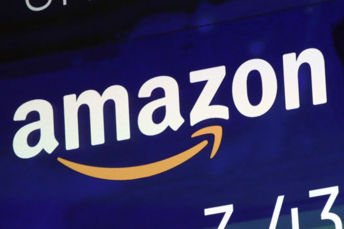 FILE - The logo for Amazon is displayed on a screen at the Nasdaq MarketSite, July 27, 2018. Britain’s competition watchdog is planning to investigate whether Amazon is harming competition and hurting consumers by giving an unfair advantage to merchants that pay for extra services. (AP Photo/Richard Drew, File)