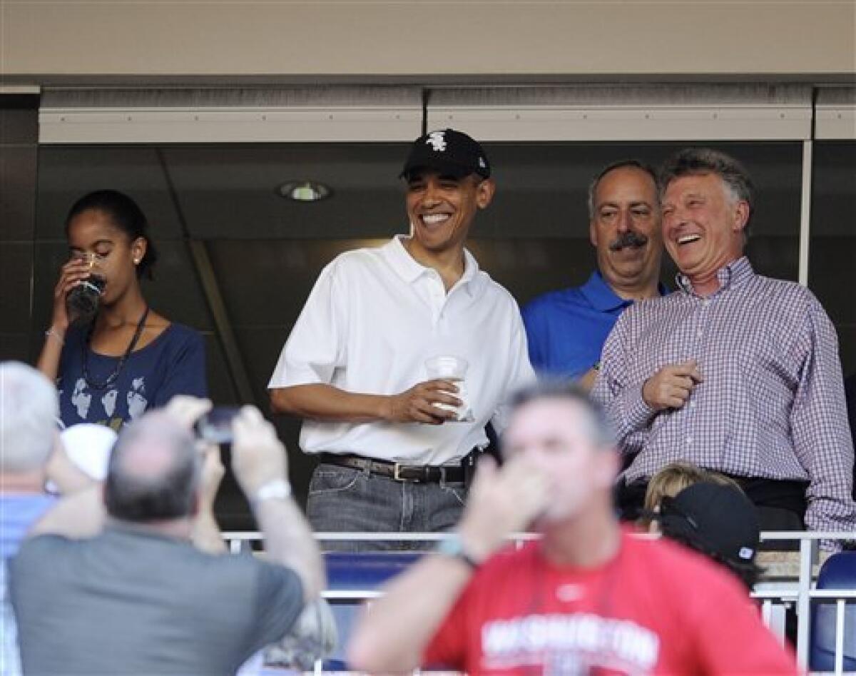 President Barack Obama, wearing a White Sox baseball cap, attends a baseball game between the Washington Nationals and the Chicago White Sox, Friday, June 18, 2010, in Washington. His daughter Malia is at left. (AP Photo/Nick Wass)