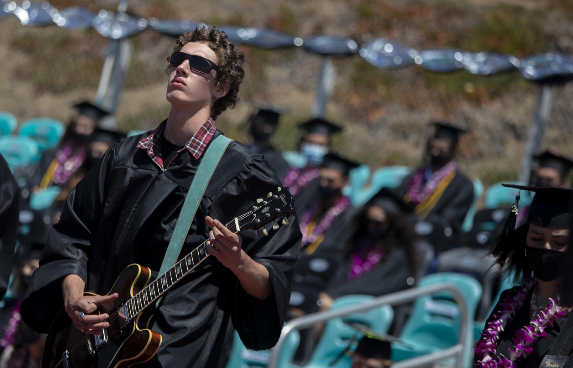 A student in sunglasses plays a guitar.