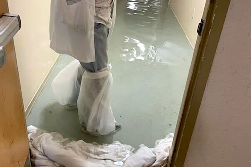 In this photo provided by Dr. Birgit Bodine, a staff member stands in a flooded hallway at HCA Florida Fawcett Hospital in Port Charlotte, Fla., Wednesday, Sept. 28, 2022. Hurricane Ian swamped the Florida hospital from both above and below, the storm surge flooding its lower level emergency room while fierce winds tore part of its fourth floor roof from its intensive care unit, according to Bodine, who works there. (Dr. Birgit Bodine via AP)