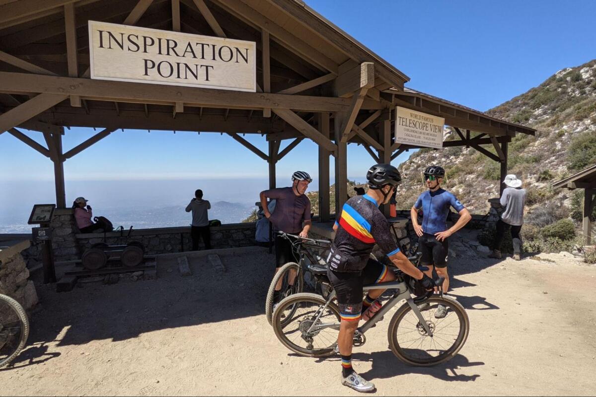 Bikers at an overlook with a wooden structure labeled Inspiration Point