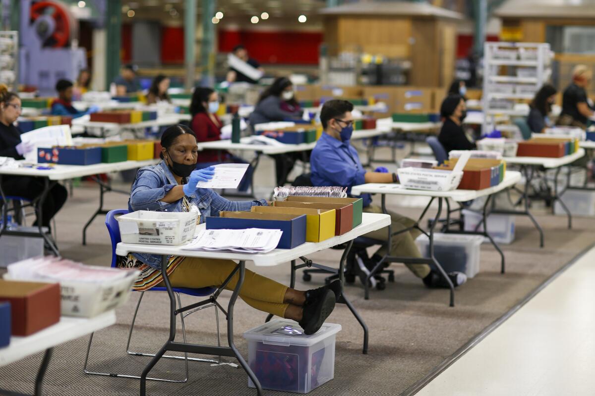 People sorting mail ballots in a warehouse.