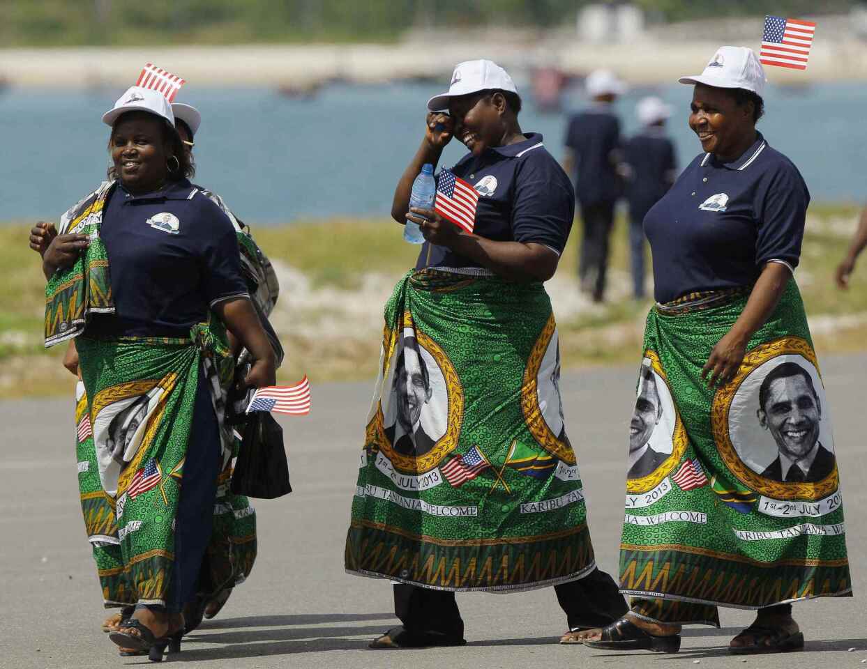 Tanzanian women wearing the local kitenge dress, bearing the image of U.S. President Obama, await the arrival of the President and the First lady in Dar Es Salaam