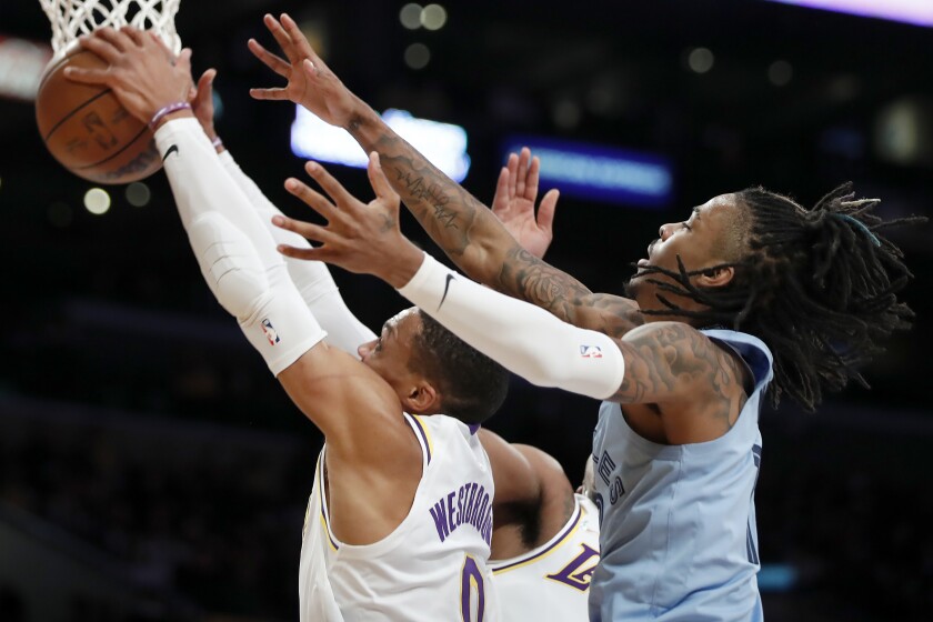 Los Angeles Lakers guard Russell Westbrook, left, grabs a rebound in front of Memphis Grizzlies guard Ja Morant, right, during the first half of an NBA basketball game Sunday, Jan. 9, 2022, in Los Angeles. (AP Photo/Alex Gallardo)