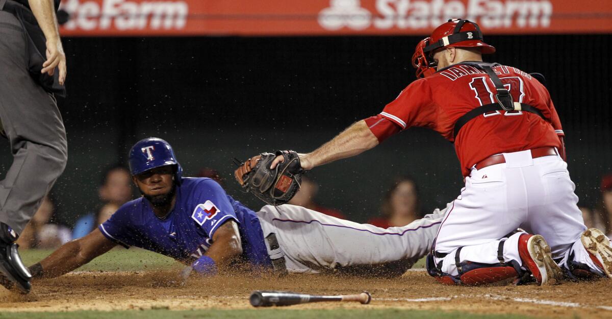 Texas’ Elvis Andrus, left, slides safely away from the tag Angels catcher Chris Iannetta during the eighth inning Saturday night.