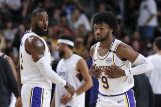 Lakers guard Bronny James steps onto the court as his father and teammate LeBron James greets him in a preseason game