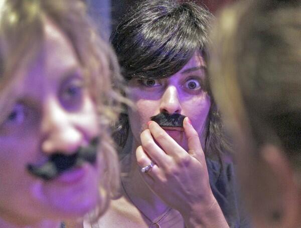 Sara Darouian, center, puts on a mustache along with girlfriends at the Los Angeles Beard & Mustache Competition at the Federal Bar in North Hollywood.