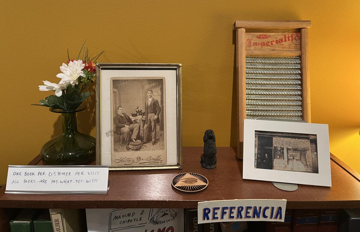 A Librería Donceles bookshelf is topped with flowers, old family pictures, a vintage washboard and the sign "Referencia."