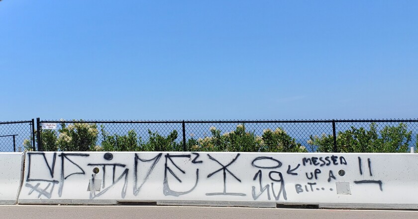 The graffiti painted on a rail along Torrey Pines Road, which was reported in late June, and was still present July 15.