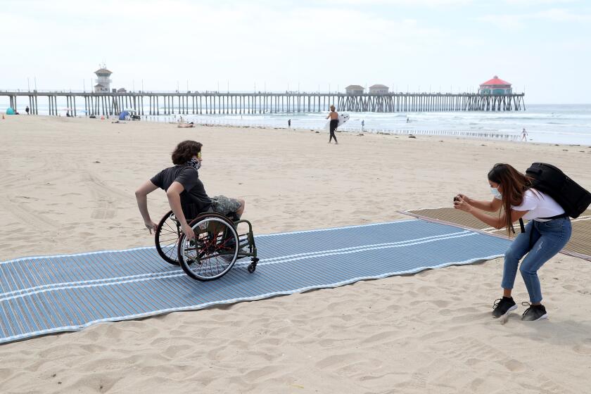Adaptive surfer Kumaka Jensen, 14, of Huntington Beach rolls out on the first Mobi-Mat in Huntington Beach during a ribbon cutting ceremony on Wednesday, May 5, 2021.